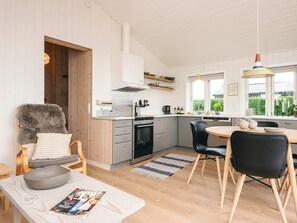 A modern kitchen with a dining area, wooden flooring, and a view of greenery outside. - 4 Person Holiday Home in Haderslev (Haderslev)