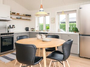 A modern kitchen with a round dining table, black chairs, and a built-in oven. - 4 Person Holiday Home in Haderslev (Haderslev)