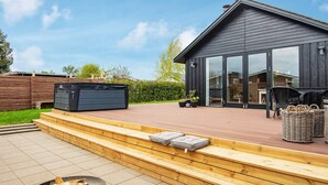 A modern house with a deck, a hot tub, and a fire pit. - 4 Person Holiday Home in Haderslev (Haderslev)
