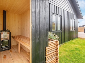 A wooden sauna with a bench and a sauna heater. - 4 Person Holiday Home in Haderslev (Haderslev)