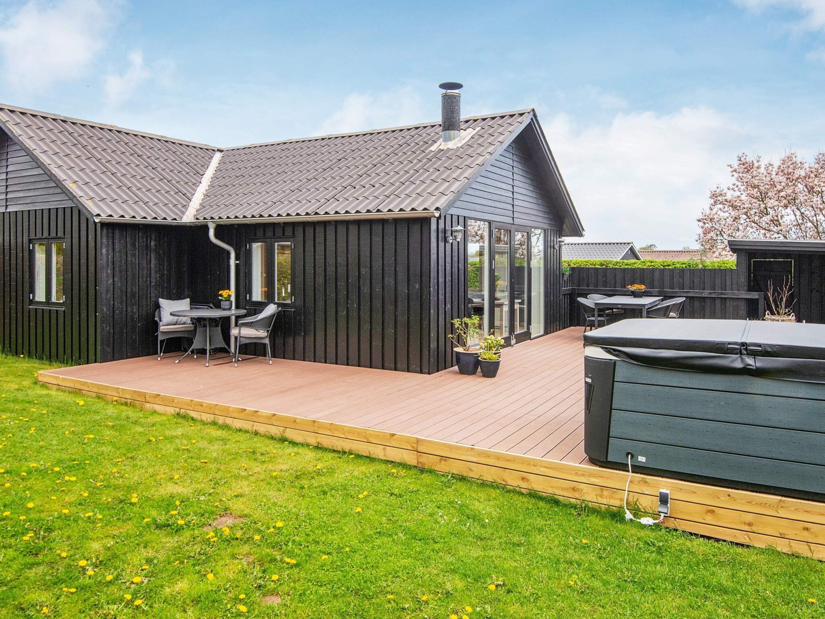 A modern outdoor patio area with a dining set and a hot tub.