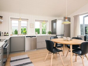 Eine moderne Küche mit Essbereich, ausgestattet mit einem runden Holztisch, schwarzen Stühlen und einem integriertem Geschirrspüler.