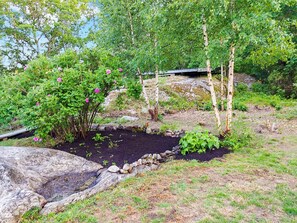 A garden with a variety of plants and trees, a small pond, and a wooden bridge. - 4 Star Holiday Home in Ellos (Ellos)