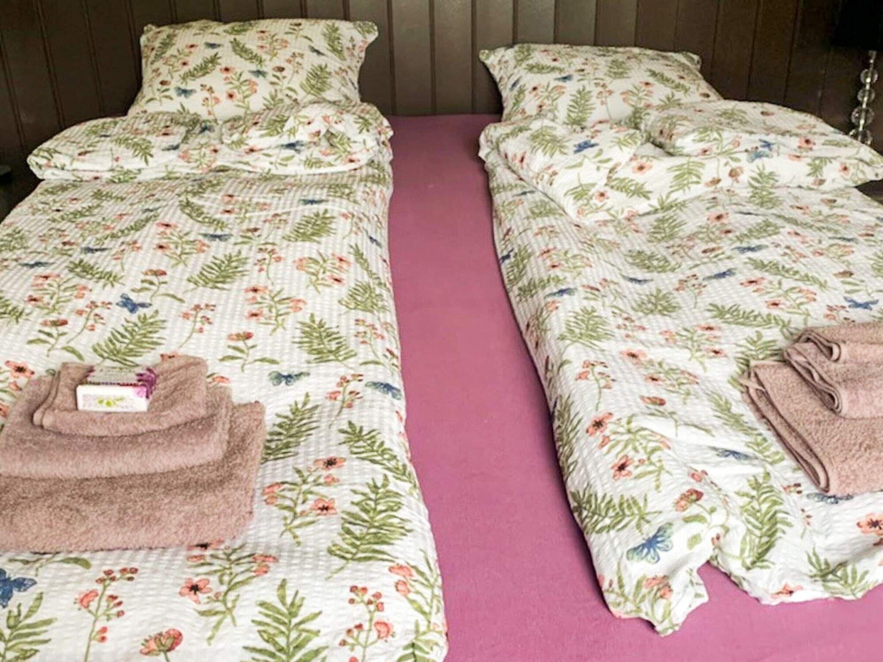 Two single beds with floral bedding and pink bedspreads.