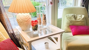A living room with a glass coffee table, a white lamp, and decorative items including a vase with red flowers and a white sculpture. - 4 Star Holiday Home in Aure (Aure)
