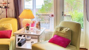 A cozy room with two yellow armchairs, a white coffee table with decorative items, and a view of greenery through large windows. - 4 Star Holiday Home in Aure (Aure)