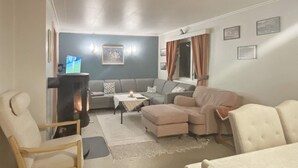 A living room with a sofa set, a chair, a small table with a candle, and a fireplace. - 8 Person Holiday Home in Stonglandseidet (Senja)