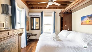 A bedroom with a bed, a ceiling fan, a desk, and a window with curtains.