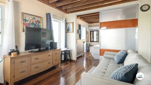 A spacious living room with a large flat-screen TV, wooden furniture, and a sofa with decorative pillows.