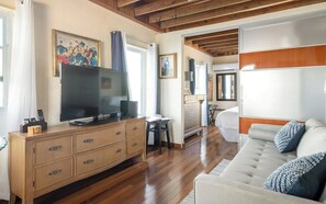 Un salón amplio con un televisor de pantalla plana grande, muebles de madera y un sofá con cojines decorativos.