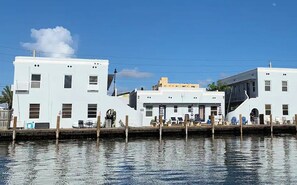 Un edificio frente al agua con un muelle, que presenta una estructura central con techo plano y dos alas laterales.