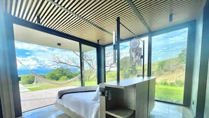 Un dormitorio moderno con una cama grande, almacenamiento integrado y vistas a un paisaje exuberante.