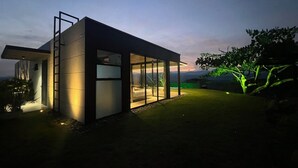 Una casa moderna con fachada de vidrio, un balcón y vistas a las montañas.