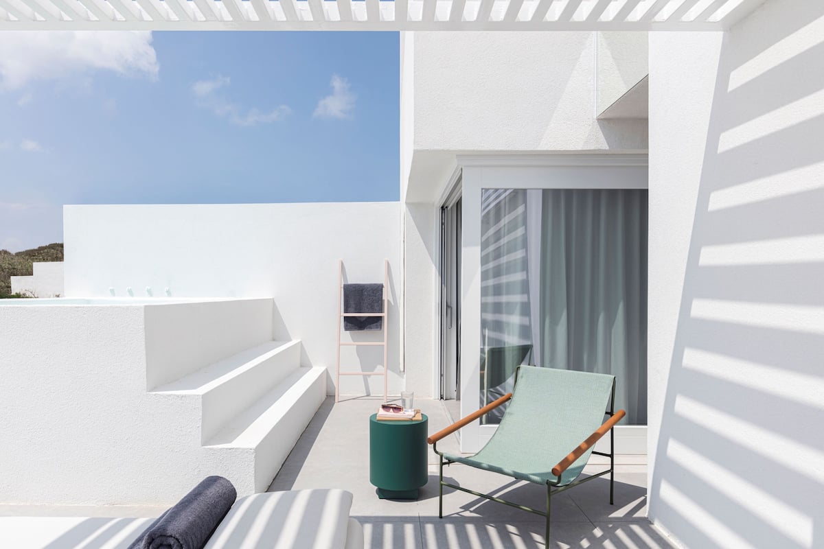 A modern balcony with a green chair, a small round table, and a towel.