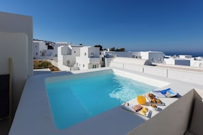 A rooftop pool with a clear view of the sea and white buildings in the background. - Neo Suites (Santorini)