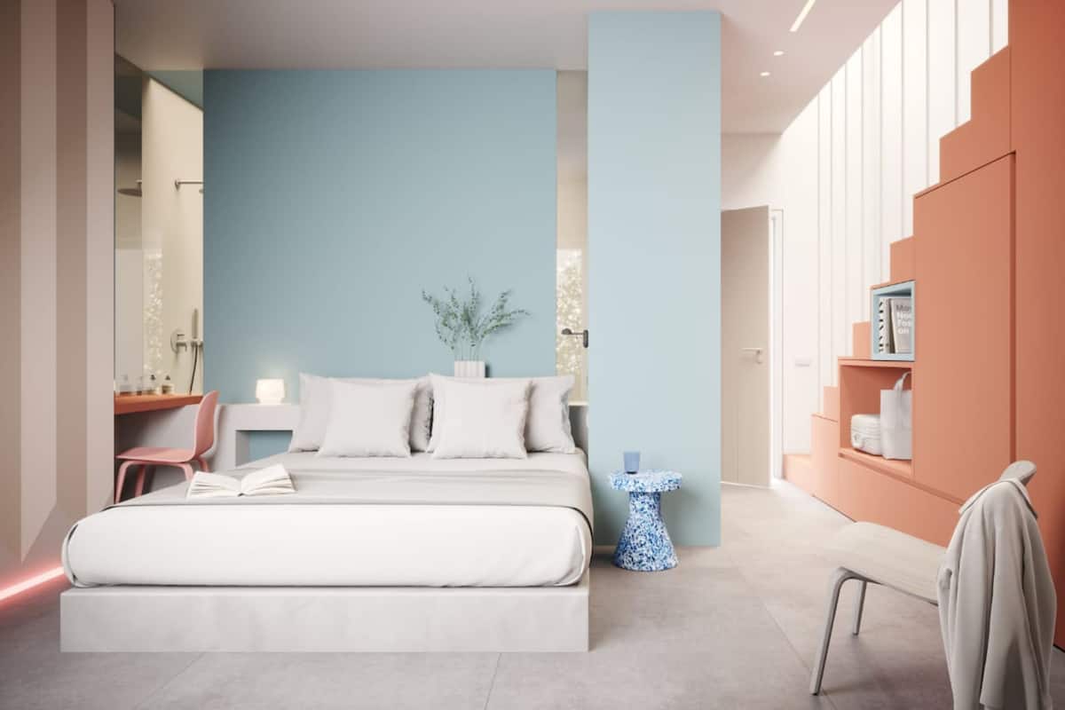 A modern bedroom with a large bed, a bedside table, a small side table, and a wardrobe.