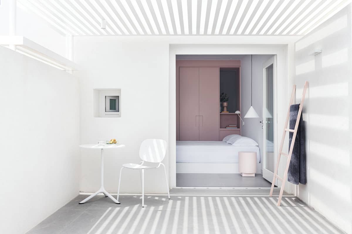A compact, modern room with a bed, a small table, a chair, and a wardrobe.