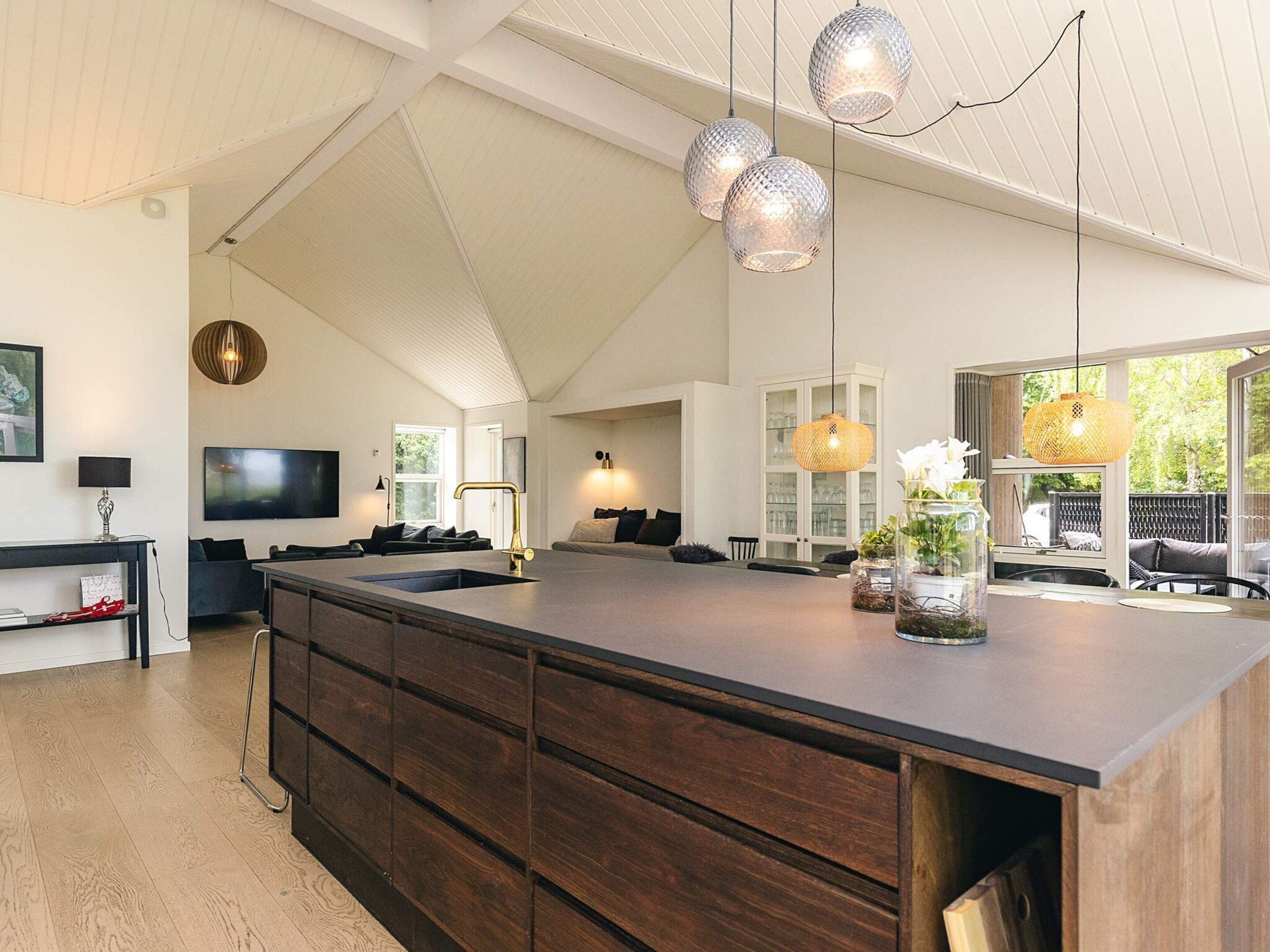 A spacious kitchen with a large island, dark wooden cabinetry, and pendant lighting.