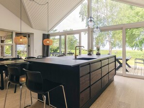 A modern kitchen with a large island, bar stools, and a view of the outdoors.