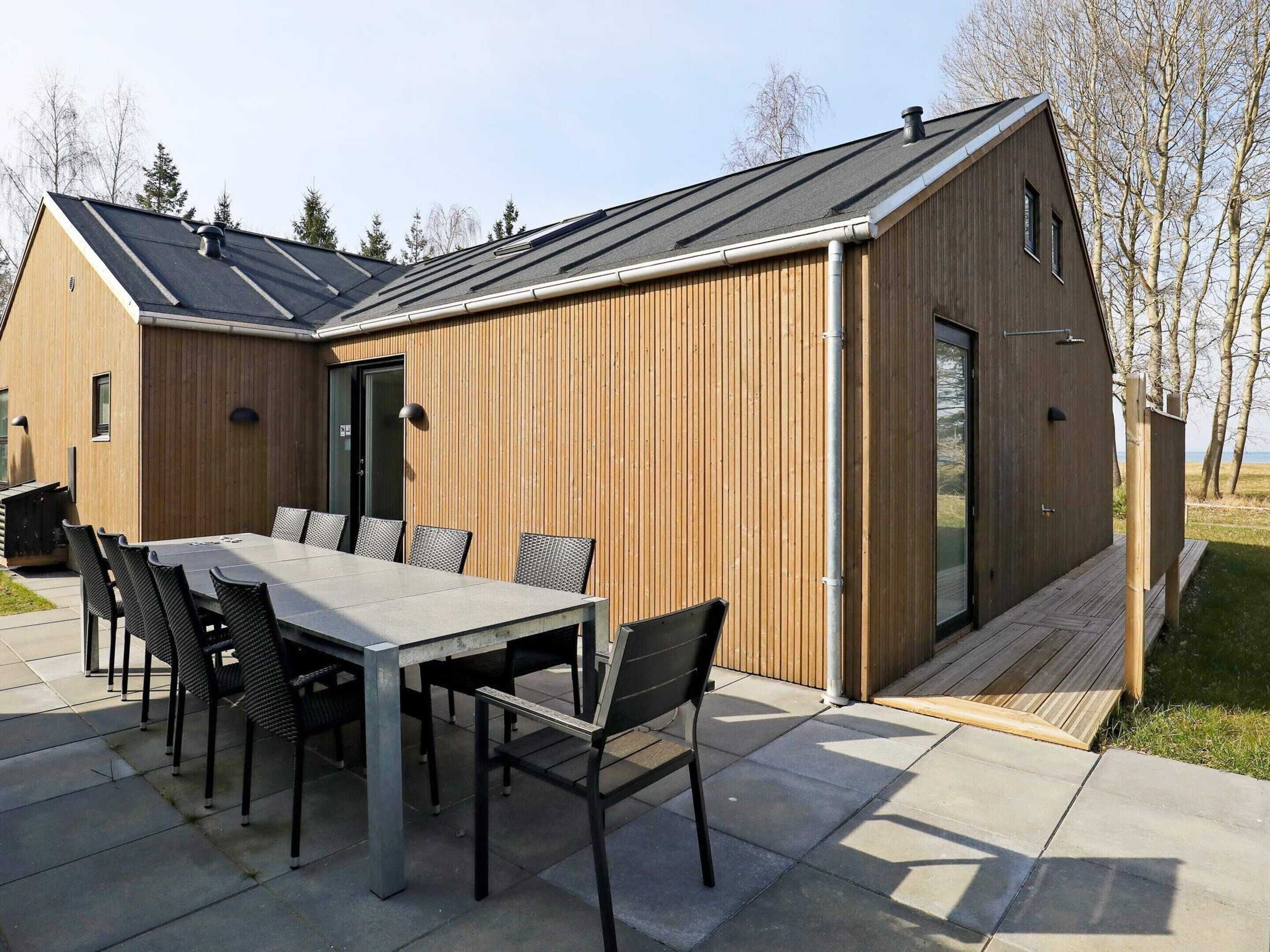 A modern wooden building with a dining area featuring a table and chairs.
