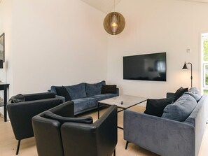 A modern living room with a sofa set, a coffee table, and a flat-screen TV mounted on the wall.