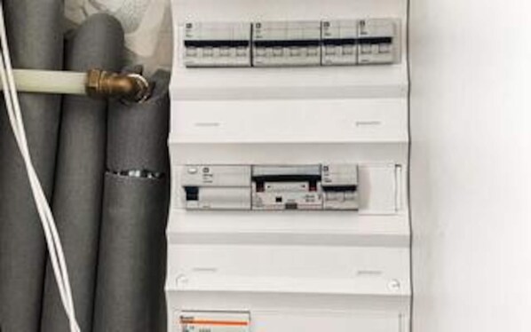 A utility panel with multiple circuit breakers and a white pipe. - 5 Star Holiday Home in Stroby (Strøby)
