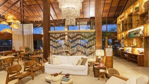 Un vaste espace salon avec un canapé blanc, des chaises en bois et un lustre.