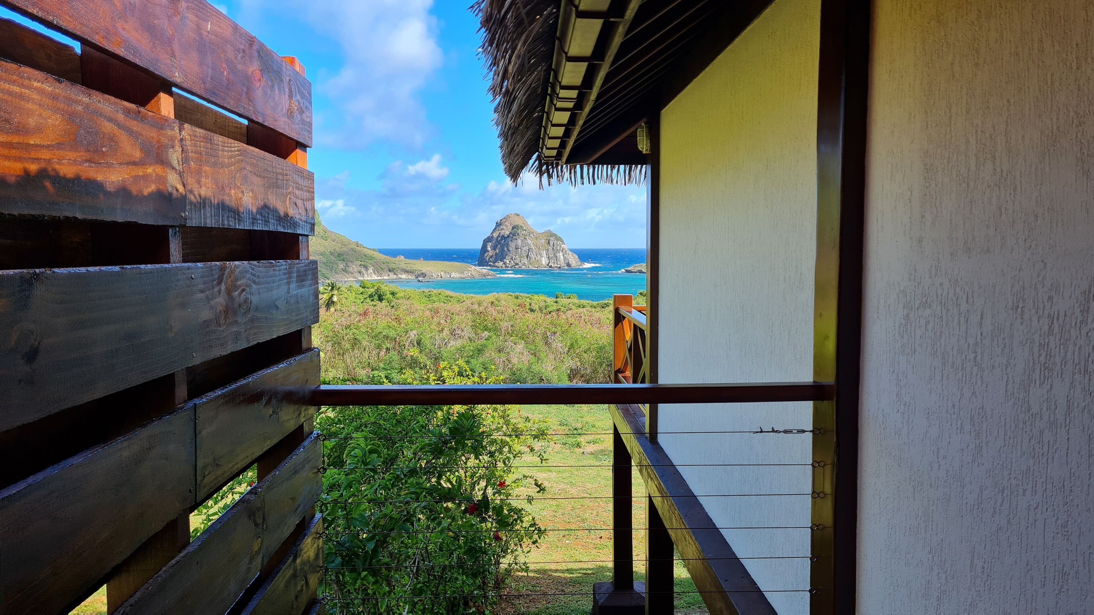 A balcony with a view of a rocky island and the ocean.