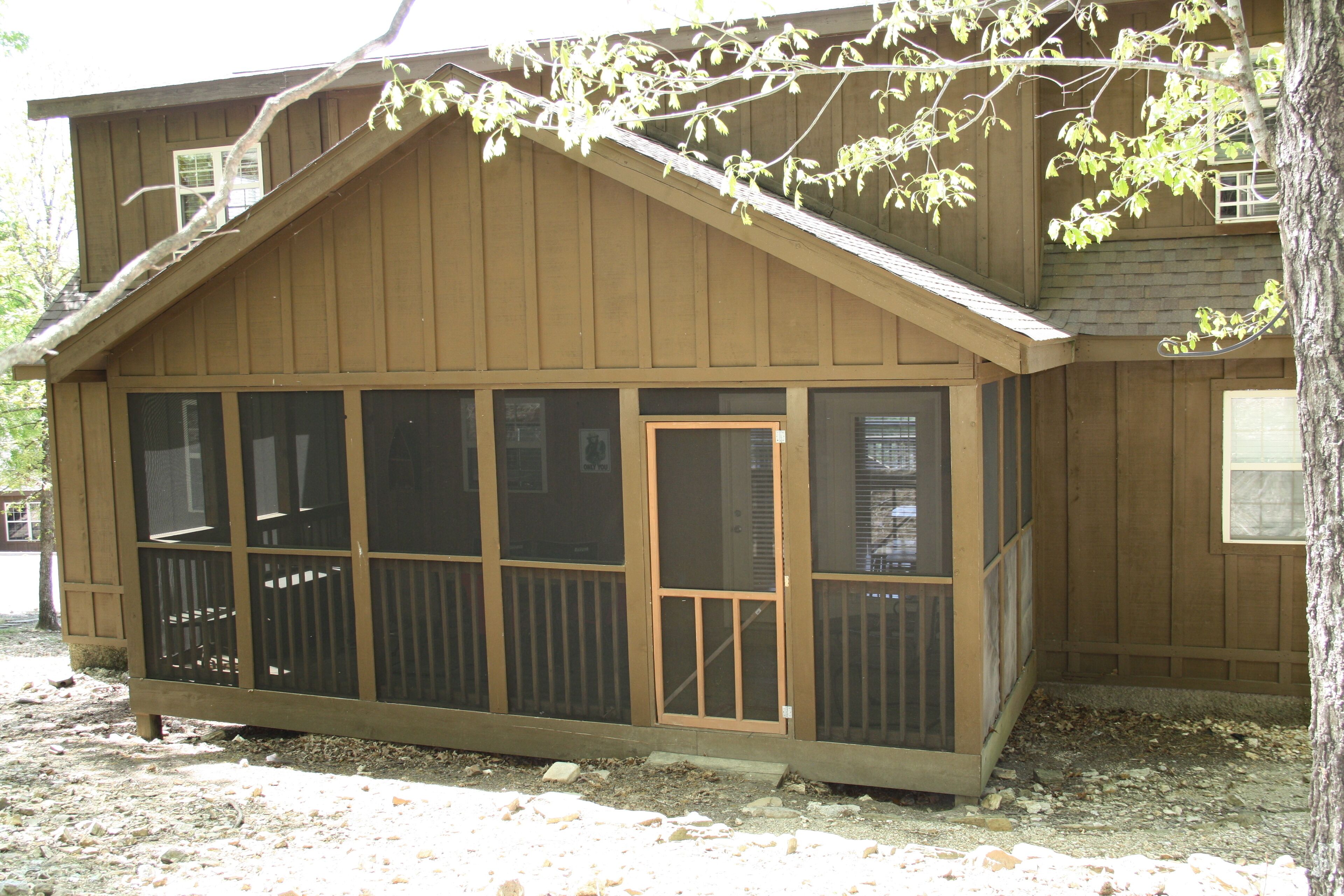 A wooden cabin with a large window, a door, and a small porch.
