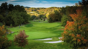 A golf course with a clear view of the fairway, sand bunkers, and surrounding wooded area.