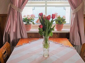 Une table à manger recouverte d’une nappe à carreaux, entourée de chaises, et un vase rempli de fleurs.