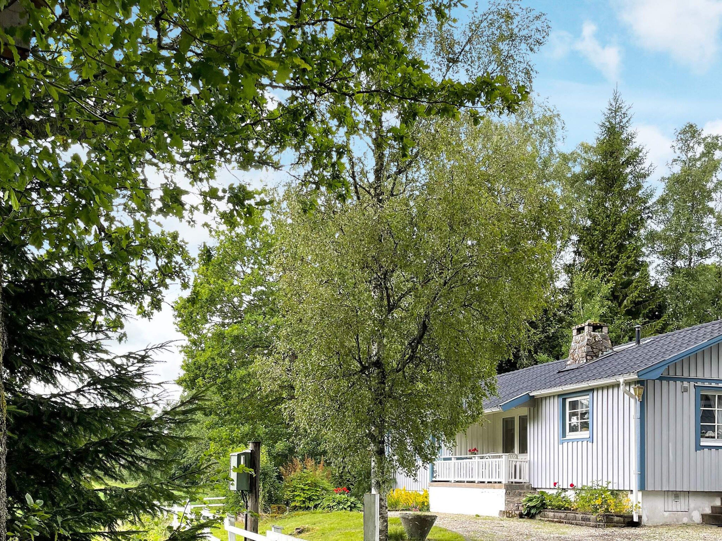 Et hus med veranda omgivet af træer og en velplejet græsplæne.