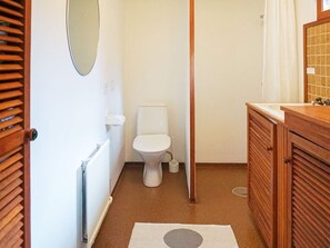 Une petite salle de bain comprenant des toilettes, un meuble en bois et un radiateur.