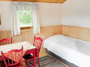 A room with a bed, a table with chairs, and a window with curtains. - 6 Person Holiday Home in Trollhattan (Trollhattan)