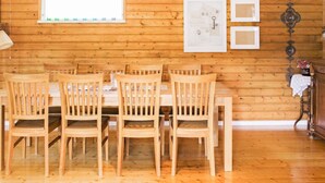 Un interior de madera con una mesa y sillas de comedor, una ventana con persianas y adornos en la pared.
