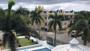 Une piscine avec un kiosque, des palmiers et un bâtiment doté de balcons en arrière-plan.