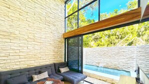 A modern living room with a stone wall, a dark sofa set, and a wooden coffee table.