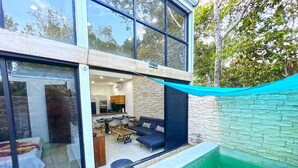 A modern house with a glass exterior, a stone wall, and a small swimming pool.