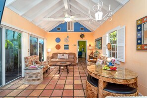 Relax in this spacious living area with a round table, comfortable sofa, and wicker chairs.