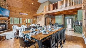 Un chalet spacieux avec de hauts plafonds, une salle à manger pouvant accueillir plusieurs personnes, une cuisine équipée d’appareils modernes et une cheminée chaleureuse.