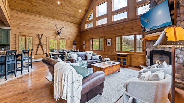 Un intérieur spacieux de chalet en bois, doté d’une cheminée, d’un coin repas et d’un espace salon confortable.