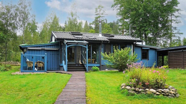 A blue house with a wooden deck leading to a porch. - 5 Person Holiday Home in Knared (Knared)