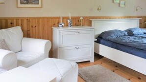 A bedroom with a white bed, a white nightstand with two drawers, a white sofa, and a wooden headboard. - 5 Person Holiday Home in Knared (Knared)