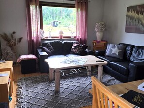 A cozy living room with a sofa, a coffee table, and a lamp. There is a window with curtains, a rug, and a painting on the wall. - 8 Person Holiday Home in Lima (Lima)