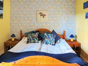 A bed with a floral-patterned headboard, two bedside tables with lamps, and a wall with floral wallpaper. - 8 Person Holiday Home in Lima (Lima)