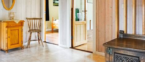 A room with a wooden cabinet, a chair, a wooden door, and a mirror on the wall.
