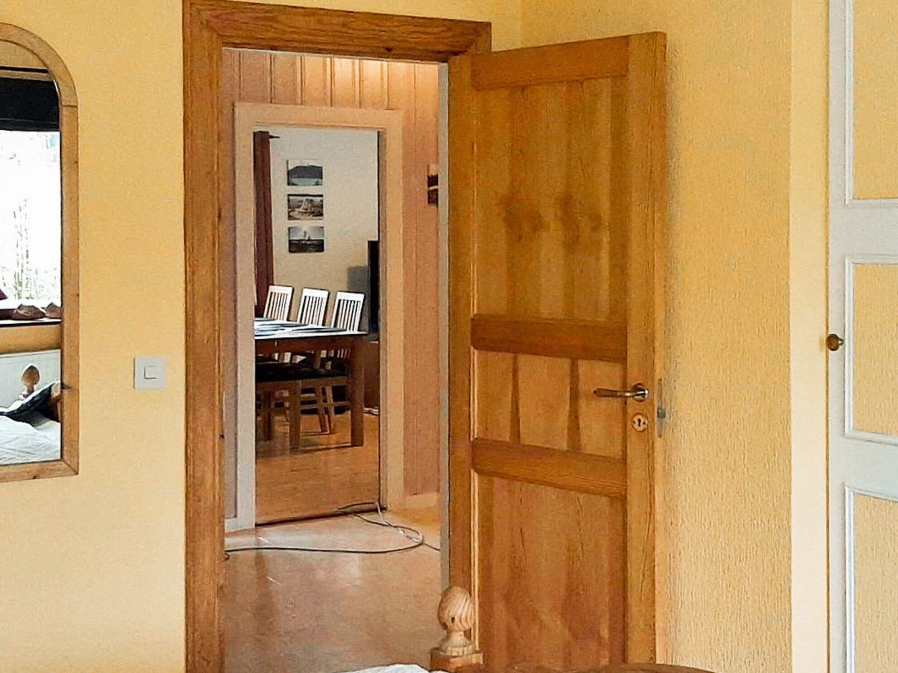A wooden door leading to a dining area with a table and chairs.