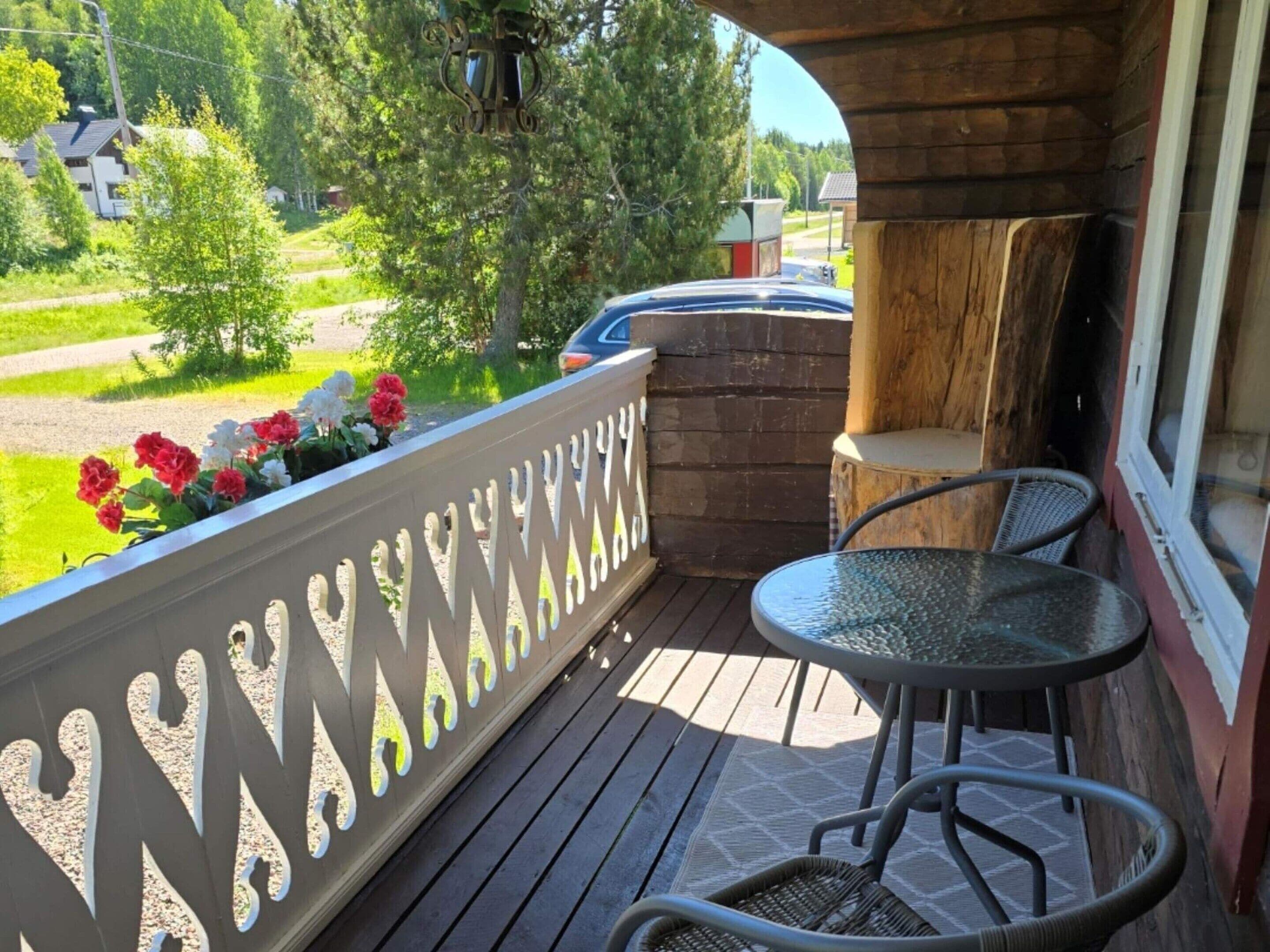 A wooden deck with a railing, a small table, and two chairs.