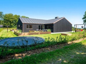 A modern house with a sloped roof, a swimming pool, and a garden with raised beds.