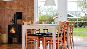 A dining area with a wood-burning stove, large windows, and a view of the outdoors.